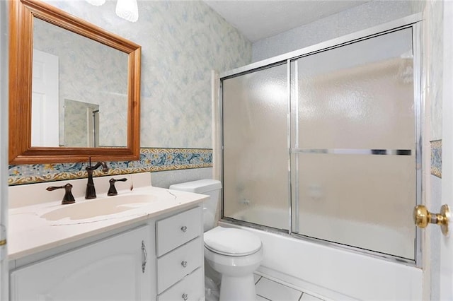 bathroom with toilet, bath / shower combo with glass door, vanity, and wallpapered walls