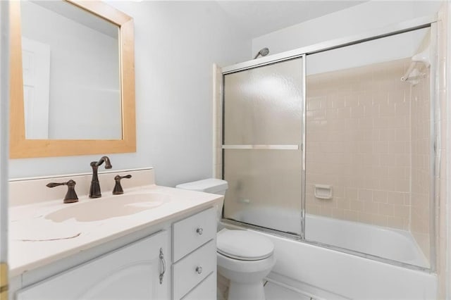 bathroom featuring toilet, bath / shower combo with glass door, and vanity