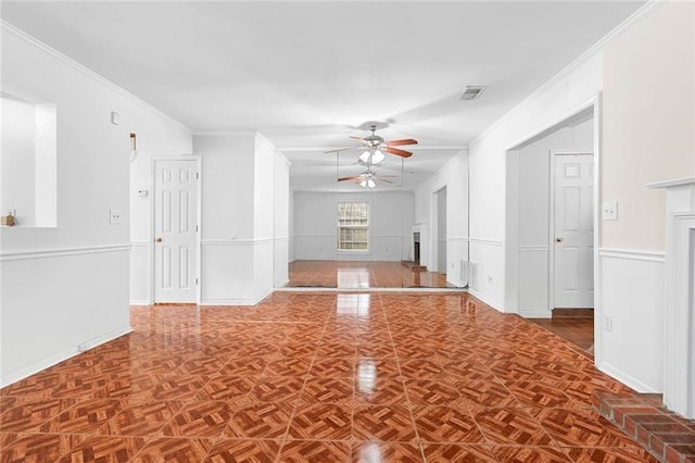 unfurnished living room with ornamental molding, a fireplace, visible vents, and a ceiling fan