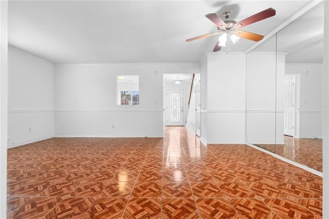 spare room with ceiling fan, baseboards, and crown molding