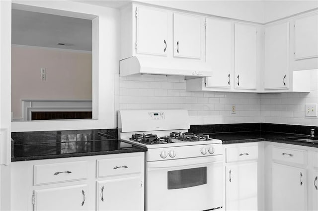 kitchen with white cabinets, dark countertops, white gas stove, under cabinet range hood, and backsplash