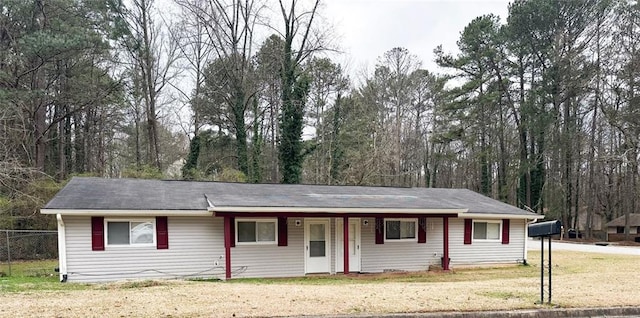 single story home featuring a front yard, covered porch, and fence