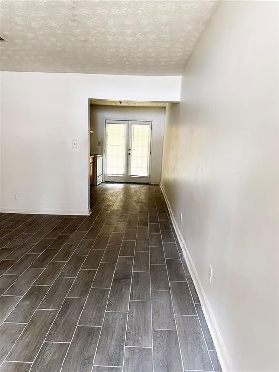 interior space featuring wood tiled floor, french doors, a textured ceiling, and baseboards