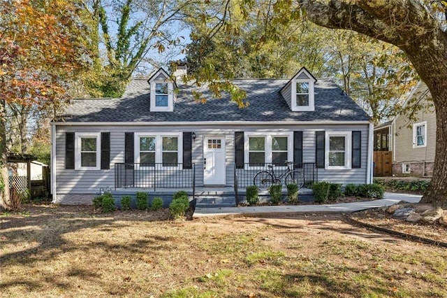 cape cod home featuring covered porch and a front lawn