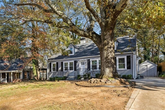 cape cod home with a front yard and a shed