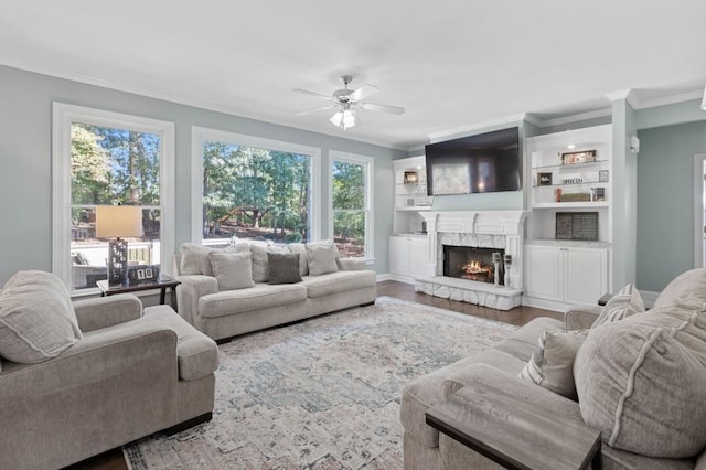 living room featuring crown molding, hardwood / wood-style flooring, a fireplace, and ceiling fan