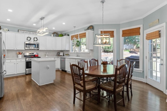 dining area featuring dark wood-type flooring, crown molding, and sink