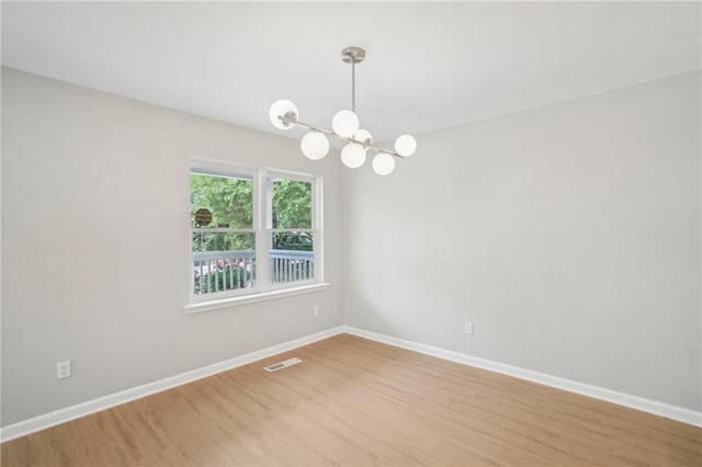 789 Third St, Stone Mountain, GA 30083 - empty room featuring a chandelier, light wood-type flooring, and baseboards