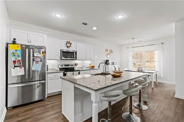 kitchen with a sink, white cabinetry, stainless steel appliances, a kitchen island with sink, and visible vents