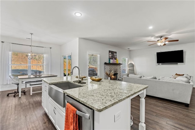 kitchen featuring white cabinets, a kitchen island with sink, a sink, dark wood-style floors, and stainless steel dishwasher