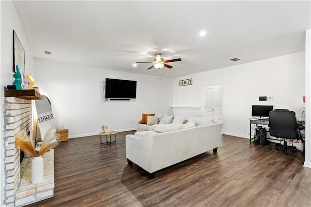 living room with dark wood-style floors, visible vents, baseboards, and a ceiling fan