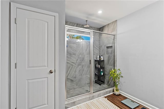 full bathroom featuring a stall shower, baseboards, and wood finished floors