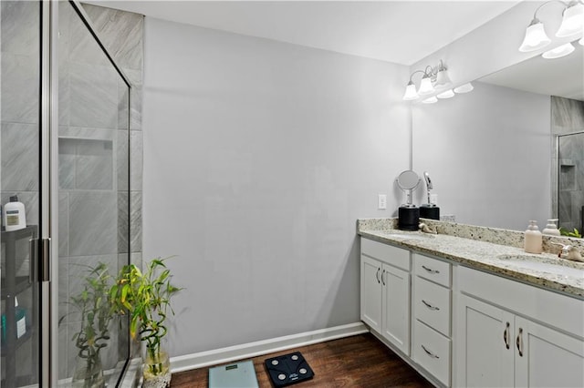 full bathroom featuring a shower stall, double vanity, baseboards, and a sink