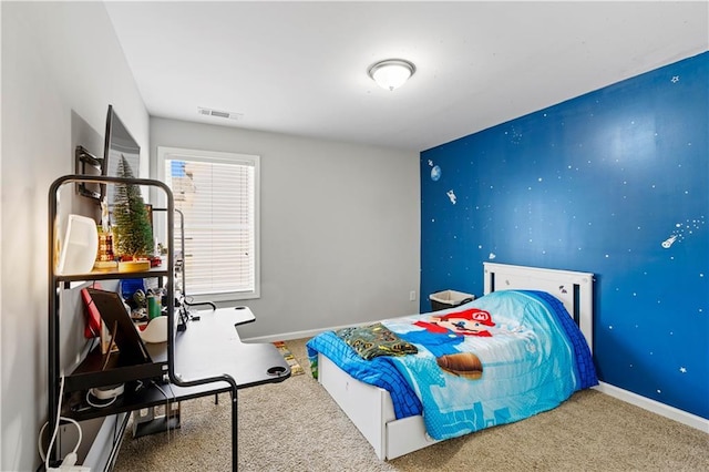 carpeted bedroom featuring baseboards, visible vents, and an accent wall