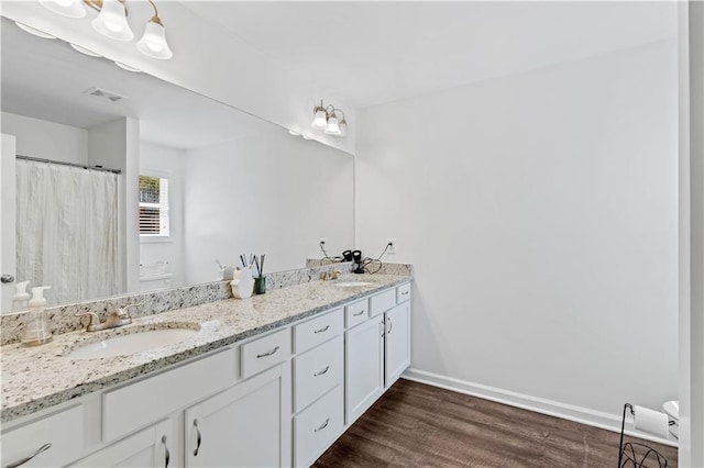 bathroom featuring wood finished floors, a sink, baseboards, and visible vents