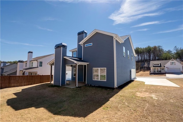 rear view of property featuring a patio area, a chimney, fence, and a yard