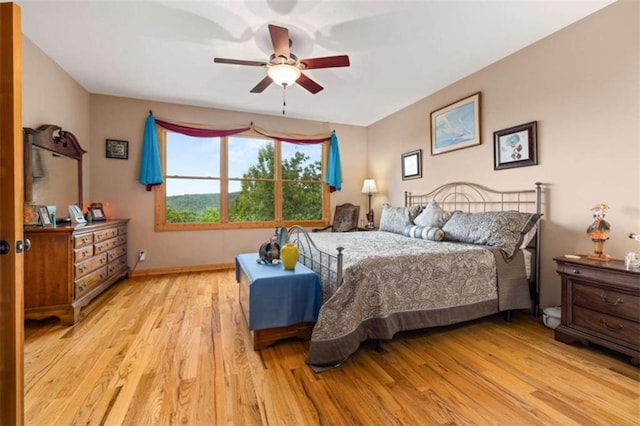 bedroom featuring light wood finished floors, ceiling fan, and baseboards