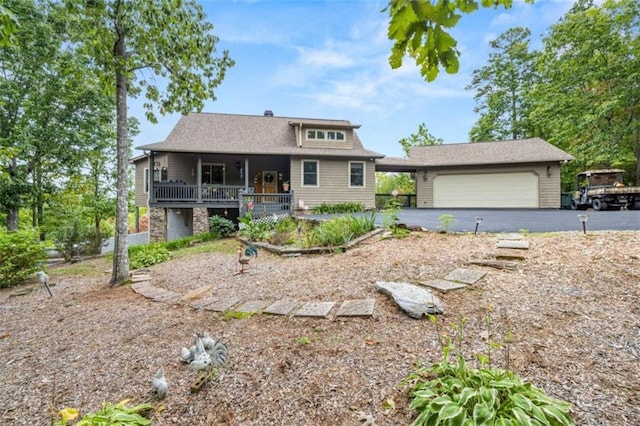 bungalow-style home featuring a garage, stone siding, covered porch, and aphalt driveway