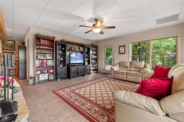 living area with light tile patterned floors, a paneled ceiling, and a ceiling fan