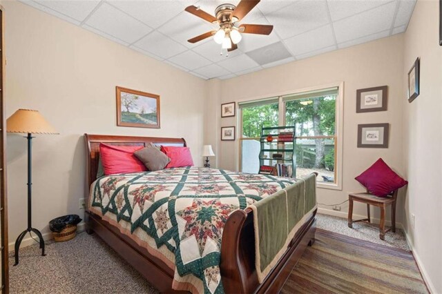 carpeted bedroom with a paneled ceiling, a ceiling fan, and baseboards