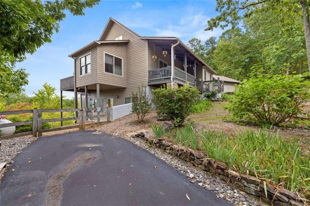 view of front facade featuring a gate, fence, and aphalt driveway