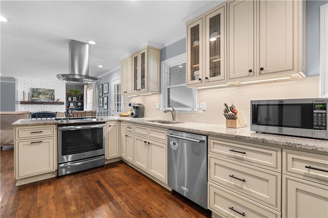 kitchen featuring island exhaust hood, ornamental molding, appliances with stainless steel finishes, dark wood-type flooring, and cream cabinetry