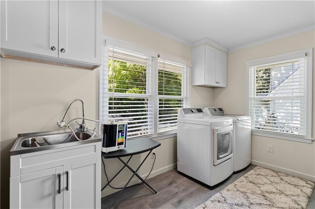 laundry area featuring ornamental molding, separate washer and dryer, light wood-type flooring, cabinets, and sink