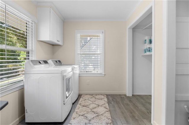 laundry area with cabinets, washing machine and dryer, light wood-type flooring, and ornamental molding