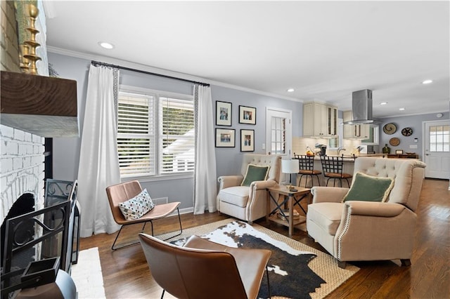 living room featuring a fireplace, wood-type flooring, a healthy amount of sunlight, and crown molding