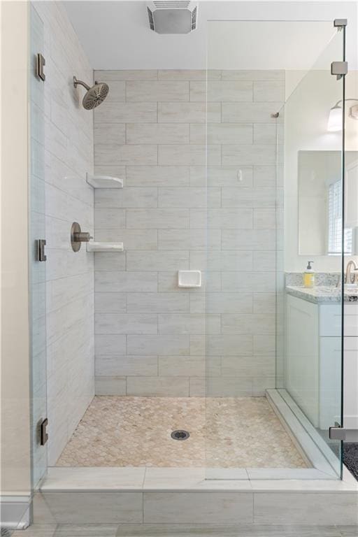 bathroom with a shower with shower door and vanity