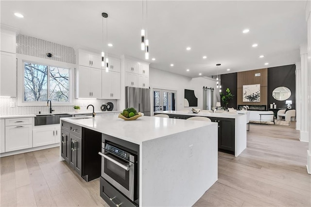 kitchen featuring an island with sink, appliances with stainless steel finishes, backsplash, and a sink