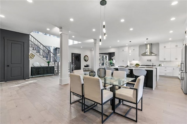 dining room featuring recessed lighting, decorative columns, light wood finished floors, and stairs