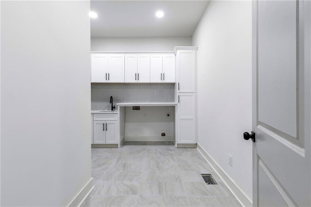 laundry room featuring cabinet space, a sink, visible vents, and baseboards