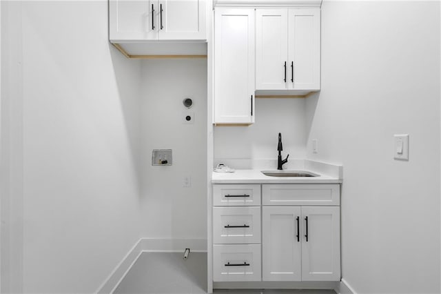 clothes washing area featuring washer hookup, cabinet space, a sink, and baseboards