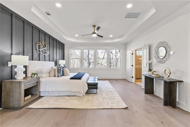 bedroom featuring a tray ceiling, light wood-style flooring, visible vents, and recessed lighting