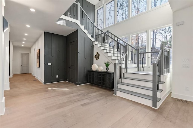 stairs with recessed lighting, wood finished floors, a towering ceiling, and baseboards