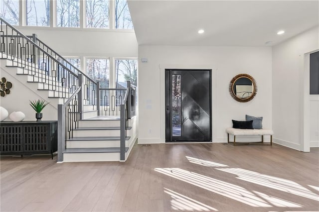 foyer with stairs, recessed lighting, baseboards, and wood finished floors