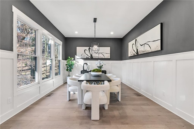 dining space with a chandelier, recessed lighting, a decorative wall, visible vents, and light wood-style floors