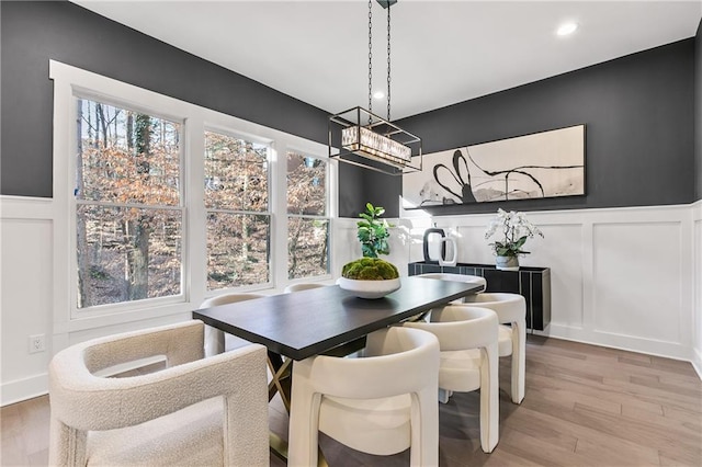 dining area with wainscoting, wood finished floors, a wealth of natural light, and a decorative wall