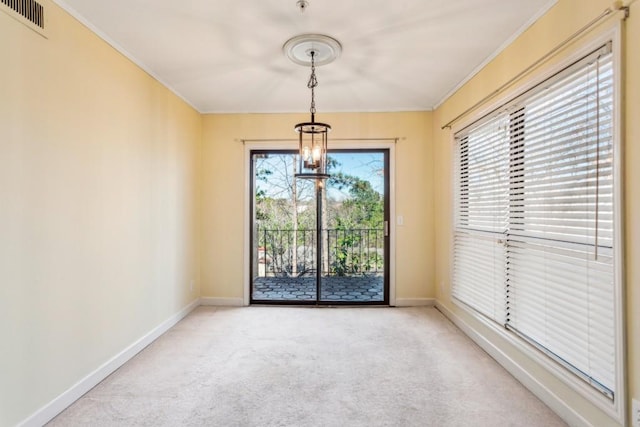 carpeted spare room featuring ornamental molding and a chandelier