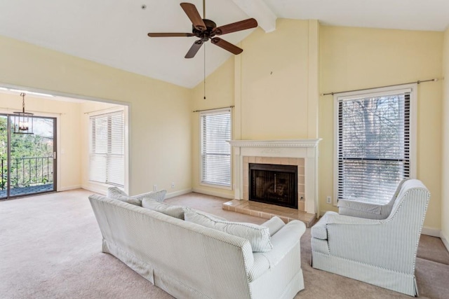 living room with high vaulted ceiling, beamed ceiling, a tiled fireplace, ceiling fan, and light carpet