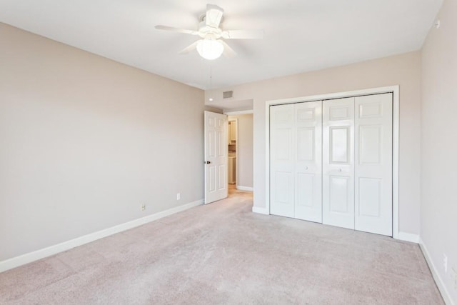 unfurnished bedroom featuring light colored carpet, ceiling fan, and a closet