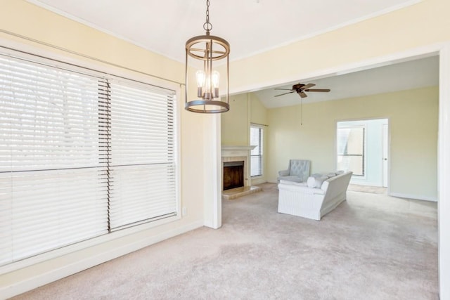 unfurnished living room with ceiling fan, light colored carpet, ornamental molding, and vaulted ceiling