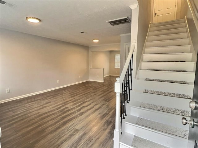 stairway with wood finished floors, visible vents, and baseboards