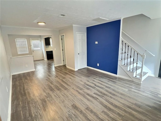 unfurnished living room with baseboards, stairs, visible vents, and wood finished floors