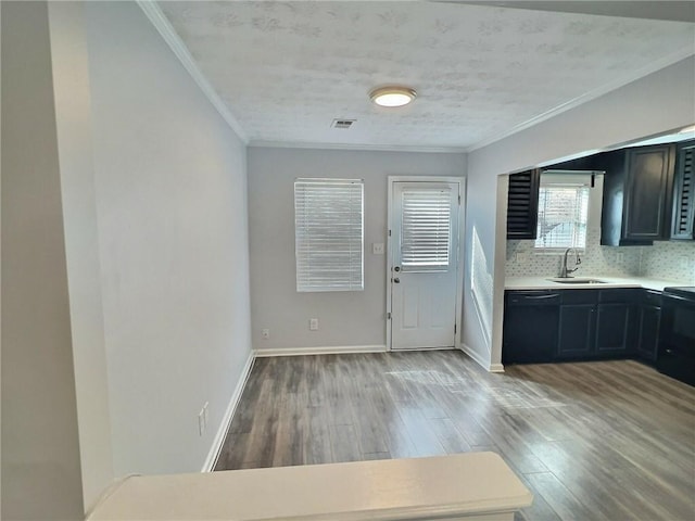 interior space with light countertops, ornamental molding, a sink, wood finished floors, and black appliances