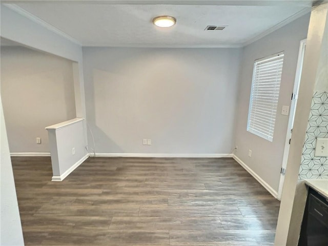 empty room with baseboards, wood finished floors, visible vents, and crown molding