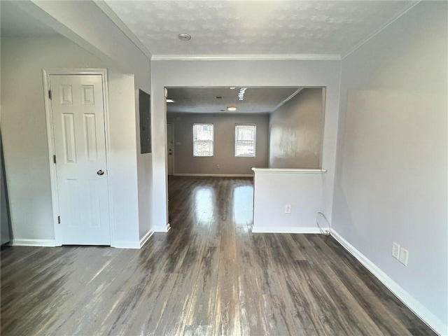 empty room featuring crown molding, baseboards, and wood finished floors