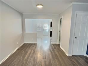 hallway with ornamental molding, baseboards, and wood finished floors