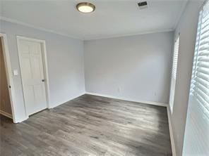 unfurnished bedroom featuring crown molding and wood finished floors